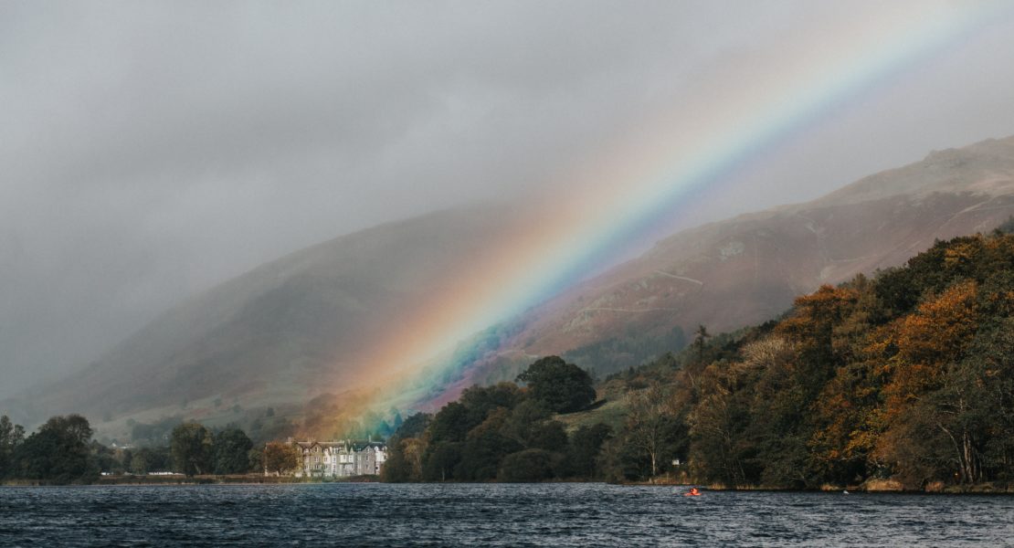 Rainbow reaches a house on a lake
